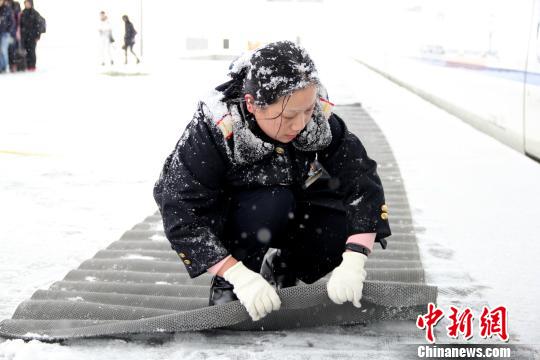 图为铁路工作人员在站台上铺设防滑垫。　秦姝　摄
