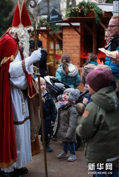 12月11日，在德国法兰克福古代雕塑博物馆开设的圣诞市场上，装扮成圣诞老人的工作人员与孩子们交谈。