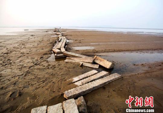 　　近年来，当鄱阳湖水位下降至枯水位时，石桥就会露出水面，成为当地一景。图为游人在古桥上行走。12月23日摄　傅建斌　摄