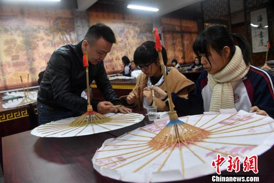 课堂上，严磊手把手地教导学生如何制作油纸伞。　吕明 摄