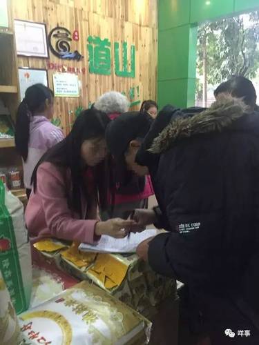值班的业务员正为一名老人登记会员资料并派发团购券。