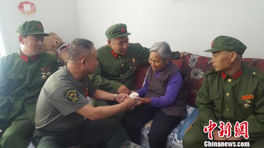 图为老兵们将慰问金送到门二柱母亲手中。　吕新颖 摄