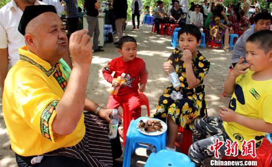号称“世界烧烤大王”的帕塔尔?吾甫尔正和他的孙子们分享自己烘烤的牛肉。　史玉江　摄