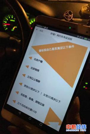 　小李拿手机展示滴滴平台的网约车司机标准 中新经纬 吴一尘 摄