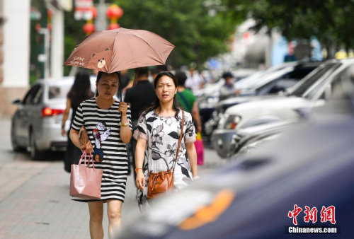 新疆乌鲁木齐市街头，民众打伞抵挡高温天气。