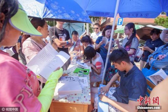 2016年6月27日，长春市，一中考考场外，几位长春市高考的状元卖“状元笔记”，50元一本，受到很多家长的追捧。图片来源：视觉中国