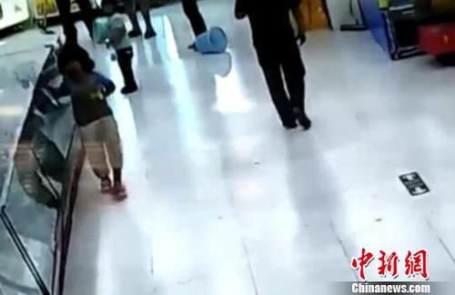 被市民拉开后，女童扶着柜台一瘸一倒的离去。(视频截图)