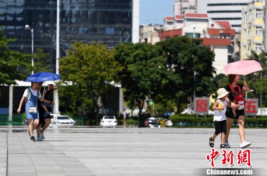 7月13日，厦门市民行走在热浪滚滚的路面上。　张斌 摄