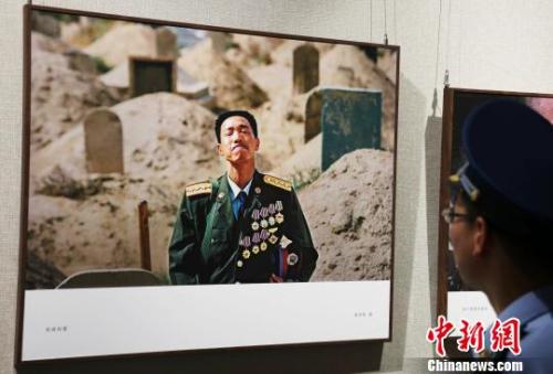 一名部队官兵正在欣赏摄影作品《英雄探妻》。　刘占昆 摄