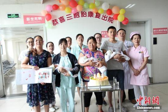 图为医护人员和三胞胎及家人合影。 钟欣 摄
