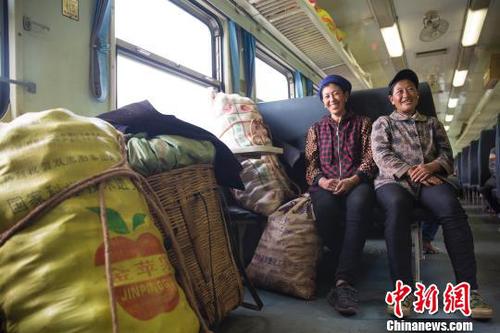 资料图：穿行大凉山的“扶贫列车”。在普雄开往攀枝花的5633次列车上，两名到喜德贩卖土豆的彝族妇女正守护着自己的货品。　龚萱　摄