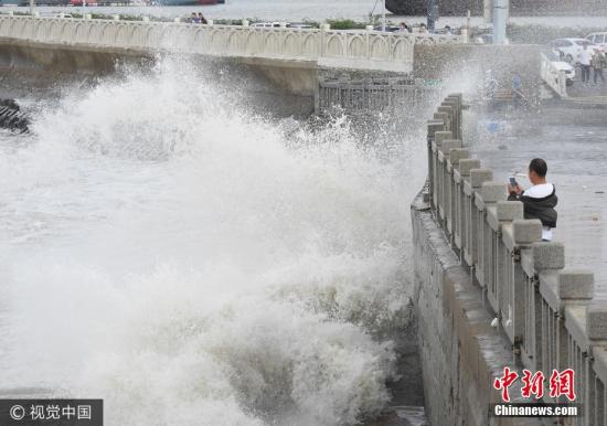 10月2日，游客在连云港市连云区海岸边观赏巨浪。当日，受冷空气影响，江苏连云港沿海出现大风，海滨掀起阵阵巨浪。据中央气象台预报，10月1日夜间至4日，冷空气将自北向南影响我国中东部大部地区，长江中下游及其以北地区有4-5级风，阵风6-7级，日平均气温或最低气温将下降4-6℃，北方部分地区降温幅度可达10℃以上。耿玉和 摄 图片来源：视觉中国