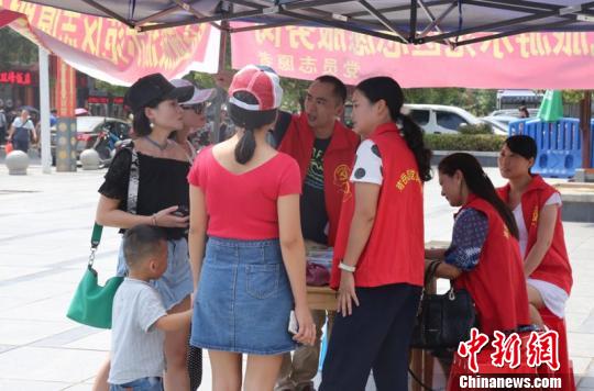 景区志愿者为游客解疑答惑、免费发放南岳旅游地图、提供景区线路指引。　文丽贵 摄