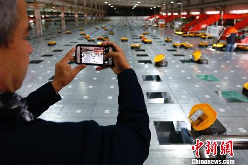 图为在申通物流公司内，记者在拍摄智能机器人自动分检系统的工作实况。　富田 摄