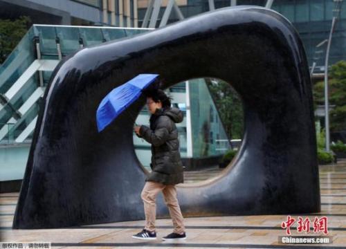 资料图：当地时间2017年10月22日，台风中的日本东京，行人顶风冒雨前行。