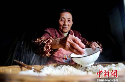 韩进先往摊凉的糯米中撒凉开水。　陶文斯 摄