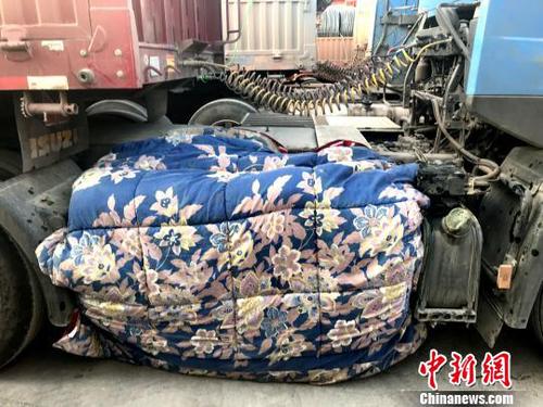 图为卡车司机用棉被为卡车“取暖”。　钟欣 摄