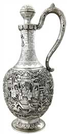 醒酒壶   Wine Decanter 晚清 通高：30.5cm；腹径：13cm；重：774g 款识：大吉     这件银壶造型独特，长颈鼓腹，通身锤揲有人物故事纹，颈部更錾刻有蕉叶纹、葡萄纹、竹枝纹，并贴焊“巴为刍夫”四字。整件器物仅有上方一球状壶塞的壶口，并无设计流口，都说明这并非盛装饮品的茶壶，而是一件醒酒壶。西方人不仅爱喝茶，同样也爱美酒，且更多的是饮用葡萄酒，葡萄酒内富含的单宁酸常常会使酒品尝的口感变涩，这也是葡萄酒需要“醒酒”这一程序的由来，而中国银匠为满足西方人的饮酒需要，创作出了银制的醒酒壶。有趣的是，醒酒需要让酒尽可能大面积的与空气接触，使得酒类的单宁酸迅速氧化挥发，而该壶并无此特点，这也是由于当时的银匠缺乏对葡萄酒的相关知识而造成的失误，只知有“醒酒”这道工序，而不知醒酒的原理，可谓是时代造就的一个美丽的误会。