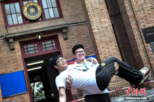 资料图：一名高考考生抱起同学在考场前合影留念。<a target='_blank' href='http://www.chinanews.com/'>中新社</a>记者 陈骥旻 摄