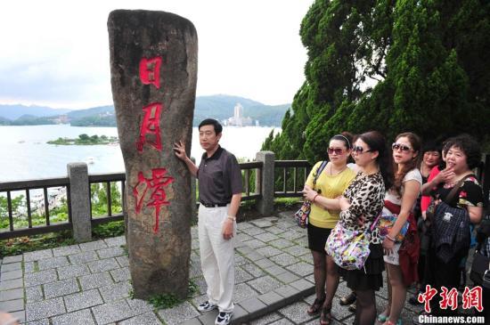 五一节来临，来自中国大陆的游客前往宝岛台湾观光，台湾故宫博物院、阿里山、日月潭、野柳、垦丁鹅銮鼻、101大楼等景点游客日益增多，旅游高潮提前到来。图为中国大陆游客排长队与日月潭标志碑留影。中新社发 陈文 摄