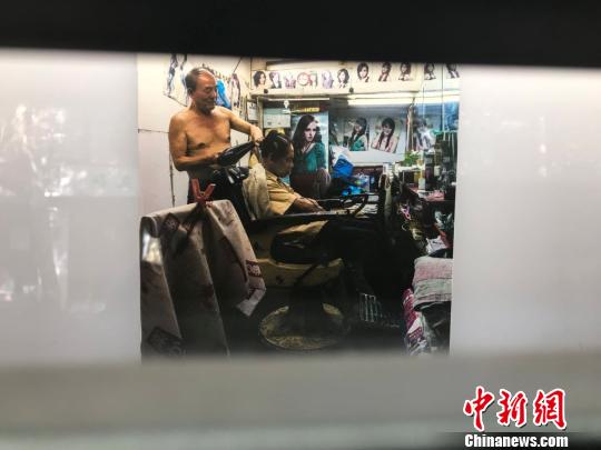 理发店里理发师正在为中年男人吹发。　王子涛 摄