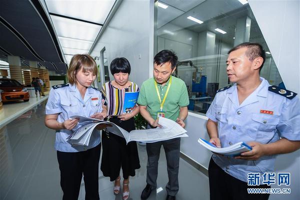 浙江省长兴县地税局工作人员在新能源企业超威集团给相应部门工作人员（左二、左三）介绍最新的税收优惠政策（2017年7月14日摄）。8