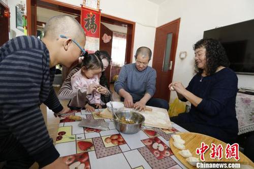 图为彭秀芳“一家四口”包饺子。(抱着玲玲的是福利院工作人员) 胡贵龙 摄
