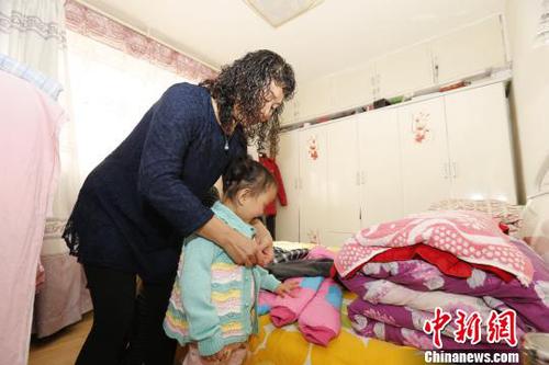 图为彭秀芳妈妈为玲玲穿新衣。　胡贵龙 摄