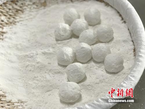 "制作元宵时，首先要将馅料做好，沾上水，再投进盛满糯米粉的笸箩内摇。<a