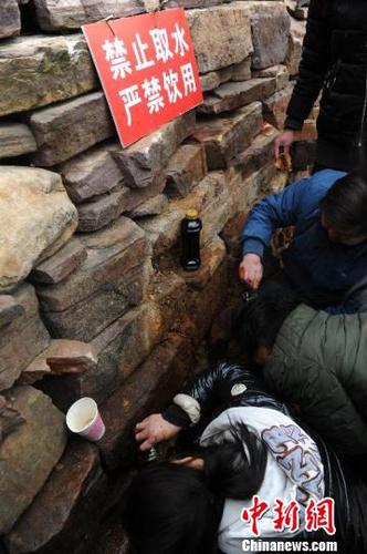 当地政府部门在渗漏不明液体的石崖处，设置明显标识，提醒群众不可饮用。　孟梅 摄