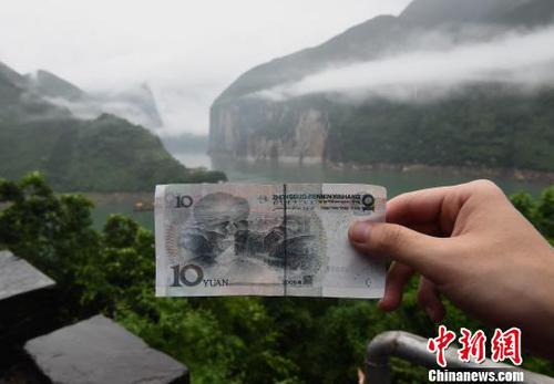 图为游客在人民币十元背景图实景地驻足参观，并拍照留念。　周毅　摄