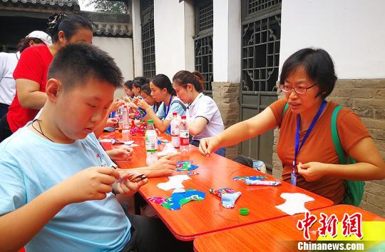太原市侨联党组书记李锦指导营员制作布老虎。　杨杰英 摄