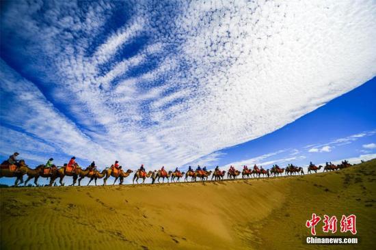 资料图：甘肃敦煌鸣沙山月牙泉景区蓝天、白云、黄沙相映成趣，每天吸引数万中外游客观光游览。 王斌银 摄