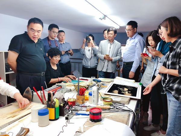 图为：杨丽丽向领导们介绍麦秸画制作过程