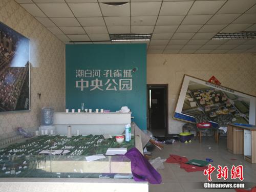 从一家已经关门的售楼处门外望进去，地上散落着废纸、条幅，沙盘上放着落灰的杀虫剂。<a target='_blank' href='http://www.chinanews.com/' >中新网</a>记者 邱宇 摄