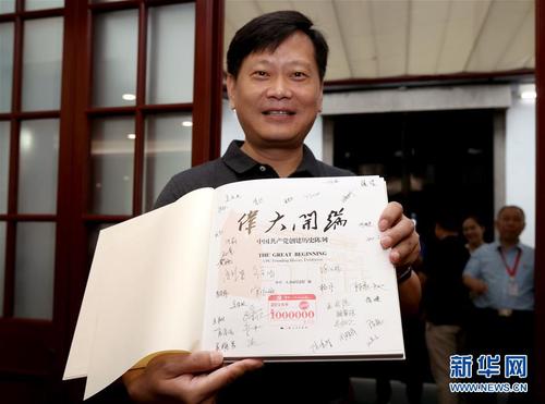 在中共一大会址纪念馆内，今年的第100万名观众刘凯在展示获赠的精装图册《伟大开端》（8月25日摄）。图册扉页上盖有“第1000000名观众”纪念章，还有纪念馆全体工作人员的签名。新华社记者 刘颖 摄