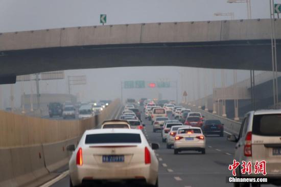 资料图：河南郑州大雾弥漫，车辆在公路上行驶。