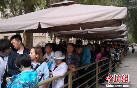 图为2018年8月中旬，莫高窟前等候参观的应急游客排成近1公里长队。(资料图) 冯志军 摄