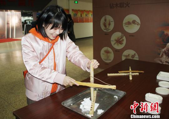 参观者现场体验“钻木取火”。　徐巧明 摄