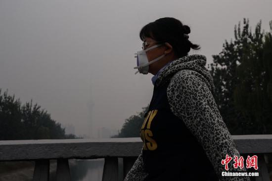 资料图：北京一名市民戴防霾口罩在户外行走，远处的中央电视塔亦被雾霾笼罩。<a target='_blank' href='http://www.chinanews.com/'>中新社</a>记者 崔楠 摄