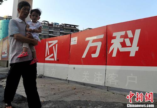 资料图：民众从万科某楼盘工地旁经过。<a target='_blank' href='http://www.chinanews.com/'>中新社</a>记者 张斌 摄