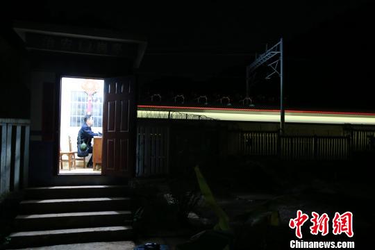夜里的南钦17号治安岗亭显得孤寂，一列动车呼啸而过。　黄军华 摄