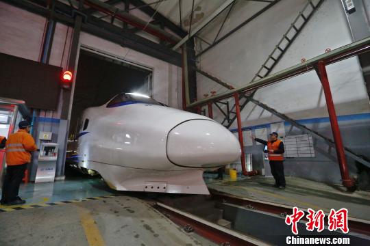 一列动车组驶入车库，机械师位列两边检查车体外观。　丁波 摄