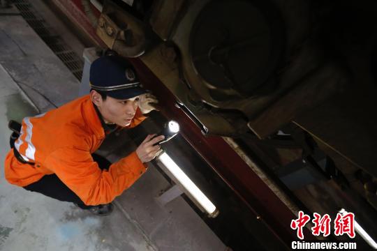 动车机械师正在检修动车车底部件。　丁波 摄