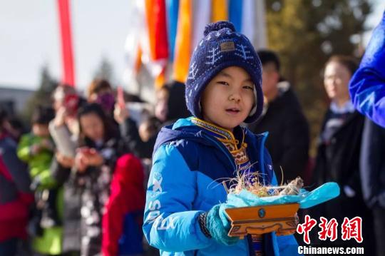 图为小孩拿着贡品准备祭火。　胡杰 摄