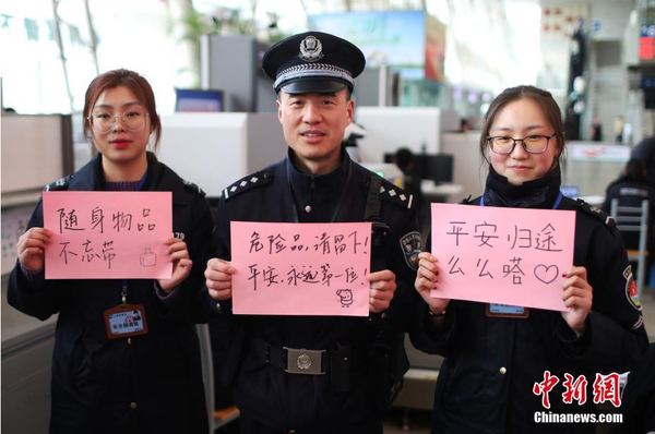 2月1日，随着春节临近，南京铁路公安处南京站派出所的民警在纸上写下“平安春运，有我们护航”、“天下无贼是我们最大的心愿”、“平安归途么么哒”等话语，用别样的方式给旅客们送上温馨的新年祝福。图为南京火车站安检处的民警和工作人员送出温馨祝福语。中新社记者 泱波 摄