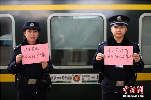 2月1日，随着春节临近，南京铁路公安处南京站派出所的民警在纸上写下“平安春运，有我们护航”、“天下无贼是我们最大的心愿”、“平安归途么么哒”等话语，用别样的方式给旅客们送上温馨的新年祝福。图为南京火车站站台上的值班民警送出温馨祝福语。中新社记者 泱波 摄