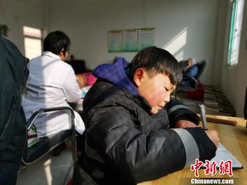 在社区服务中心，刘奉智母亲为村里人按摩，刘奉智在一旁写作业。　郝学娟 摄