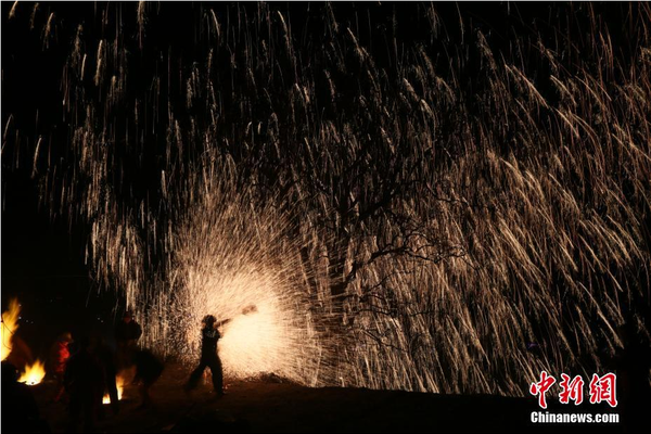 该村“打树花”的习俗已延续了近600年，村民将生铁融成铁水后，再用特制的木板将铁水击打至树上，顿时绽放出万点“铁花”。中新社记者 陈昊 摄