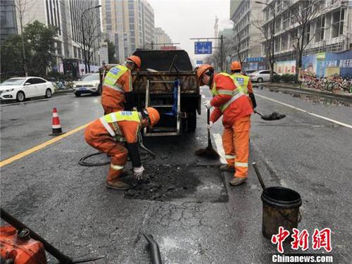 环卫工人修补雨天侵蚀的沥青路面。　西湖区城管局提供 摄
